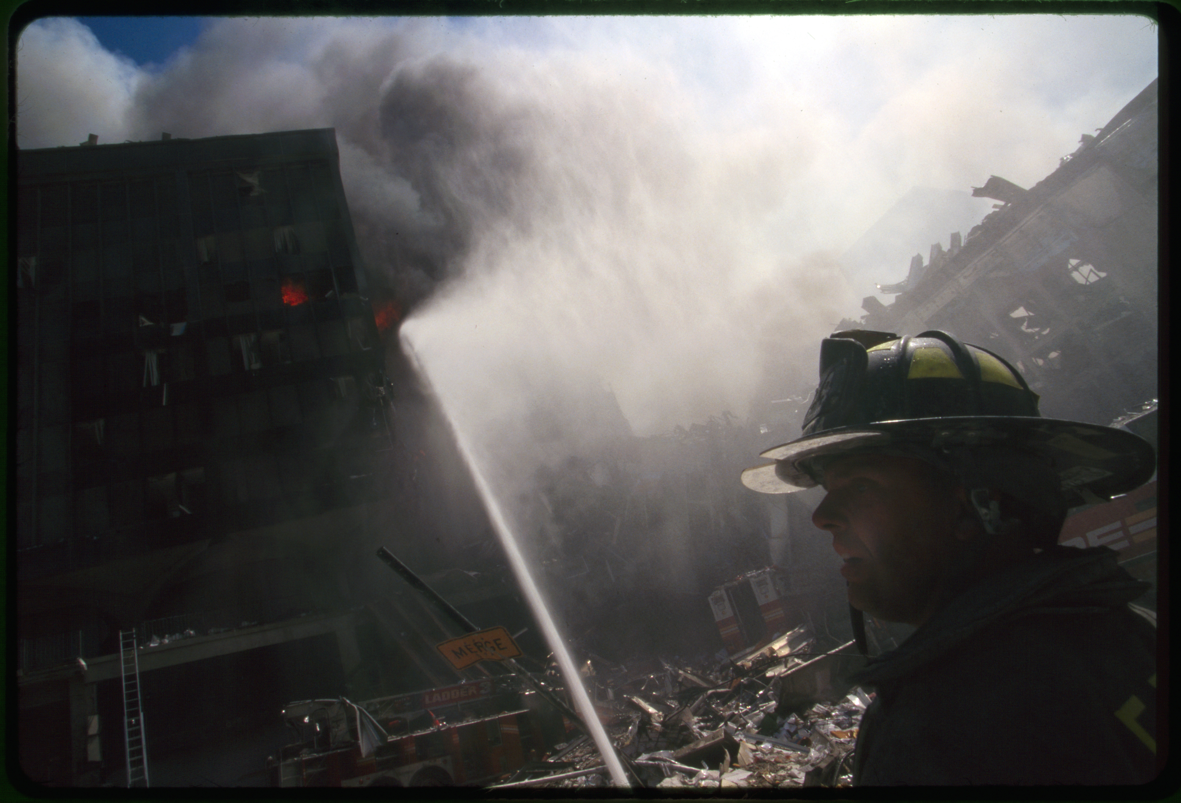 Fire fighter in front of burning building and rubble following September 11th terrorist attack on World Trade Center, New York City